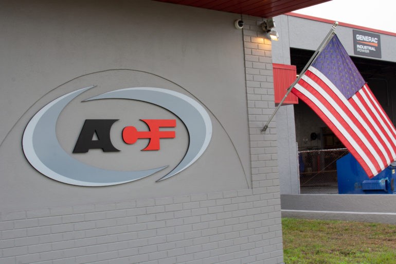 ACF Standby Systems logo mounted on a building exterior with the American flag proudly displayed beside it.