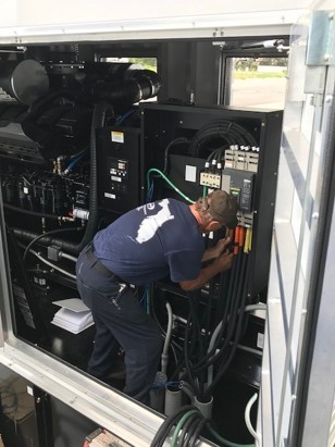 A technician diligently working on the intricate wiring and components inside an ACF Standby Systems electrical cabinet.